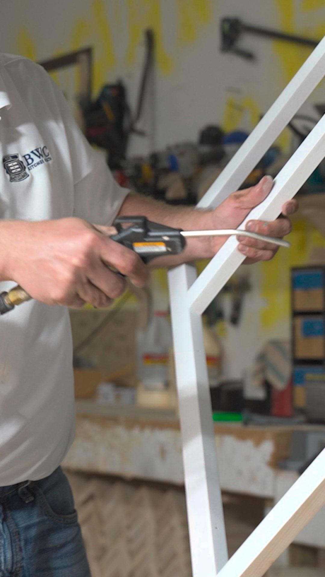 Blowing dust off a primed cabinet face frame with compressed air