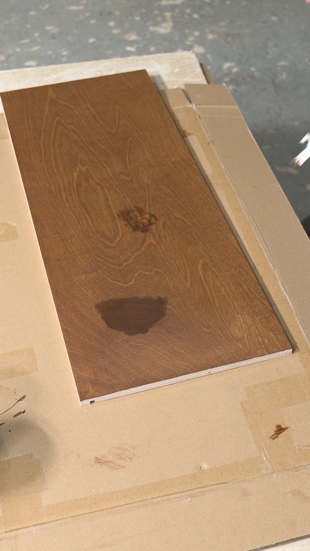 Dark dried stain spots on a stained cabinet panel before the fix