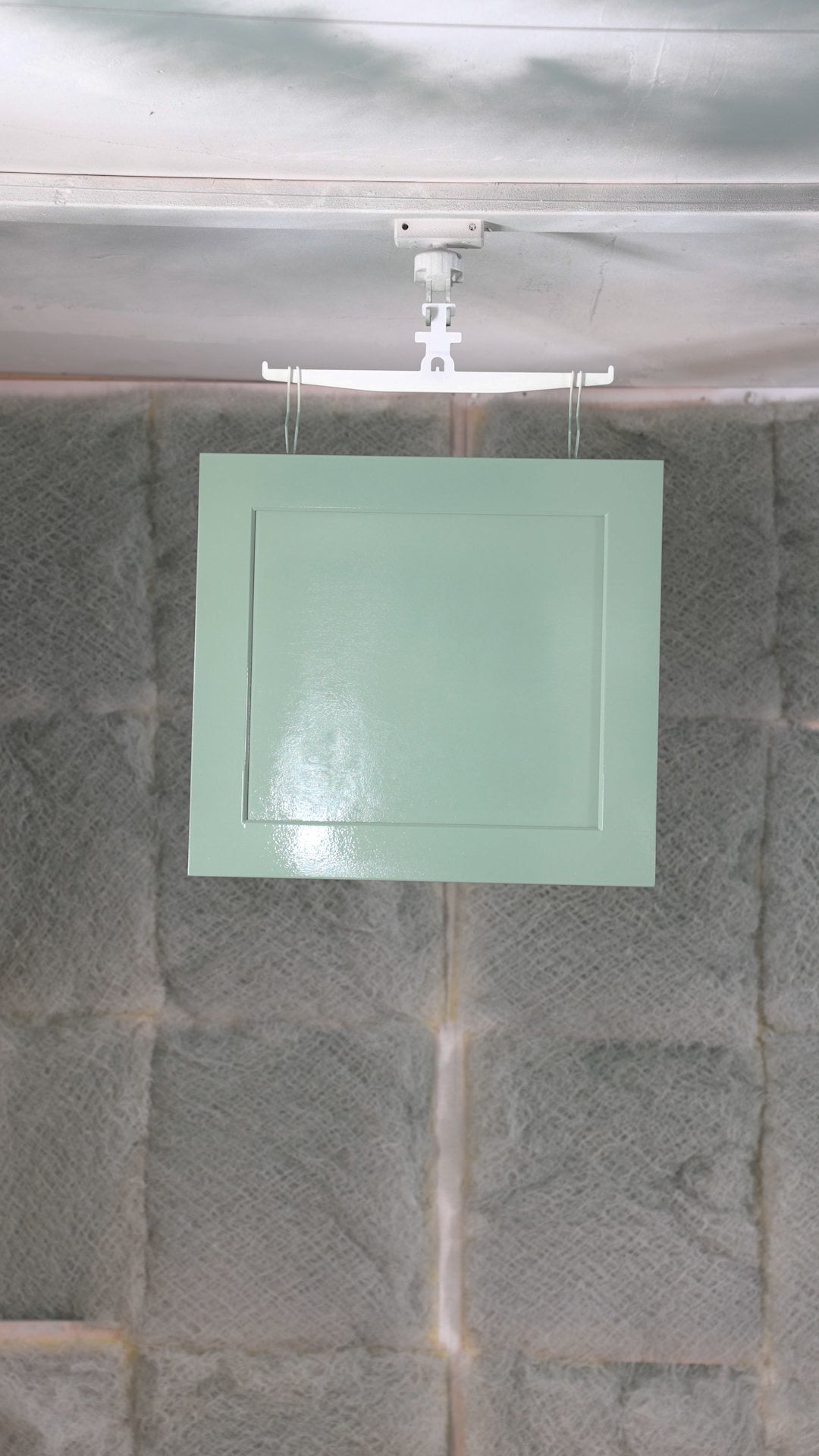 Freshly sprayed enamel top coat leveling out on a green shaker cabinet door
