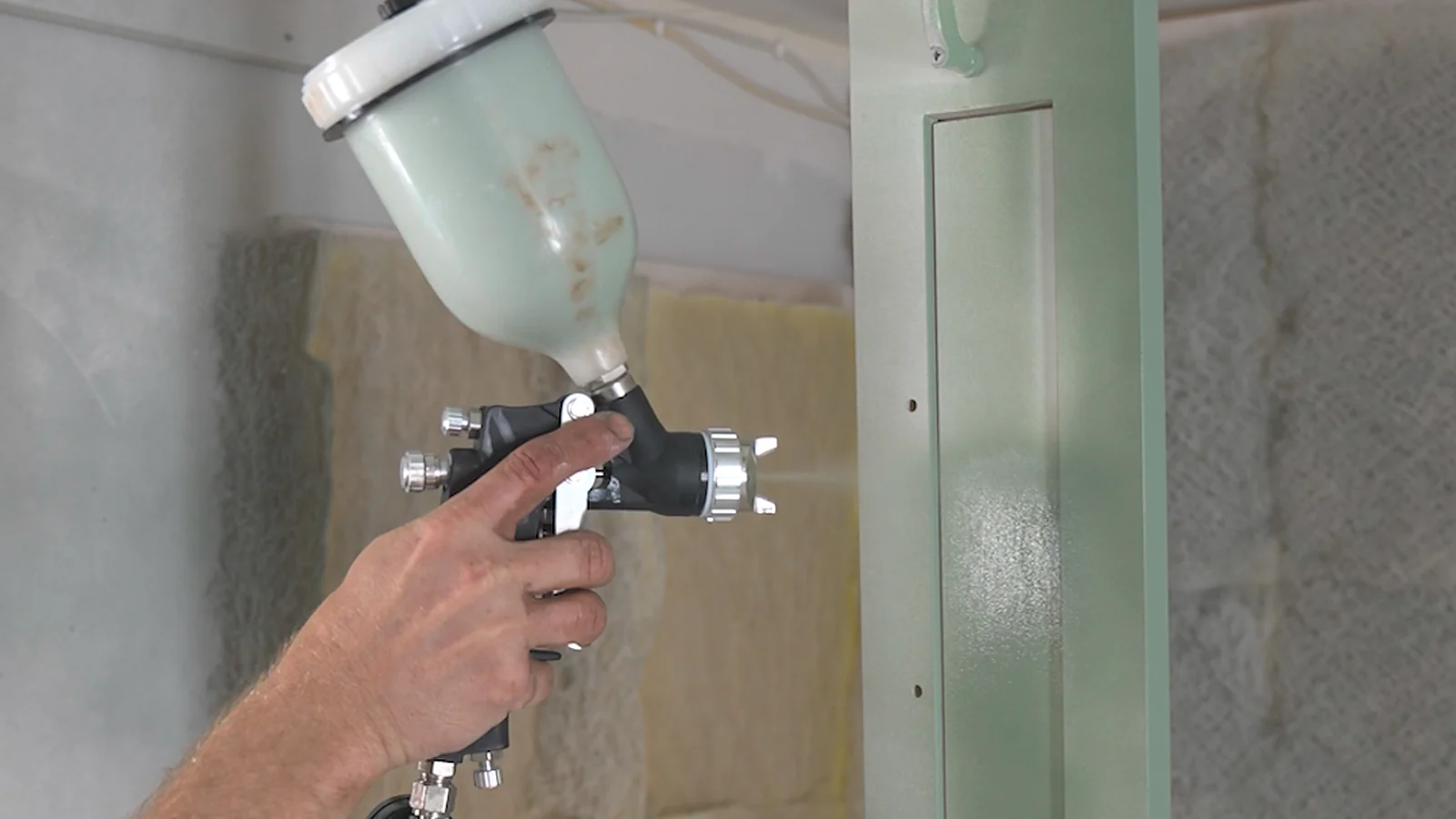 how to paint unfinished cabinets: spraying a raw birch shaker door with a cup gun
