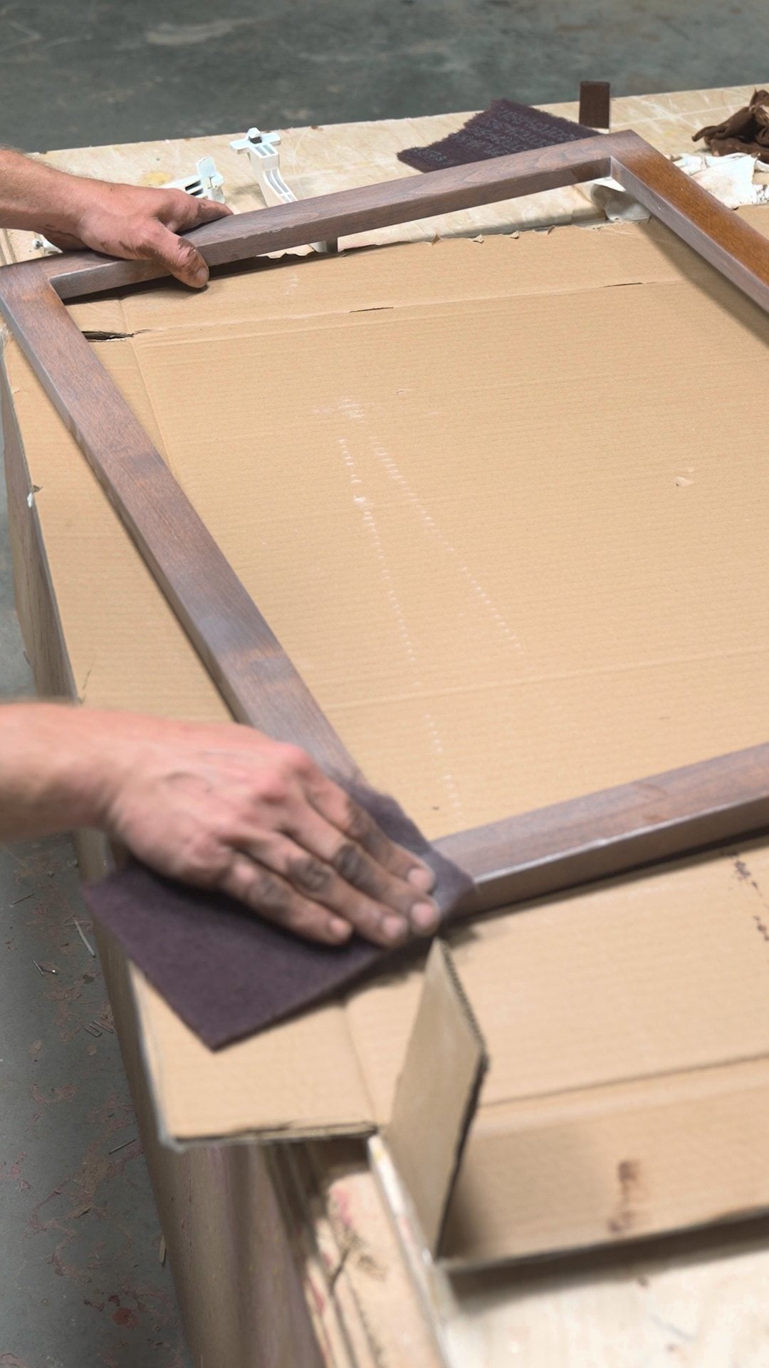 Smoothing the sealer coat on a stained face frame with fine synthetic steel wool
