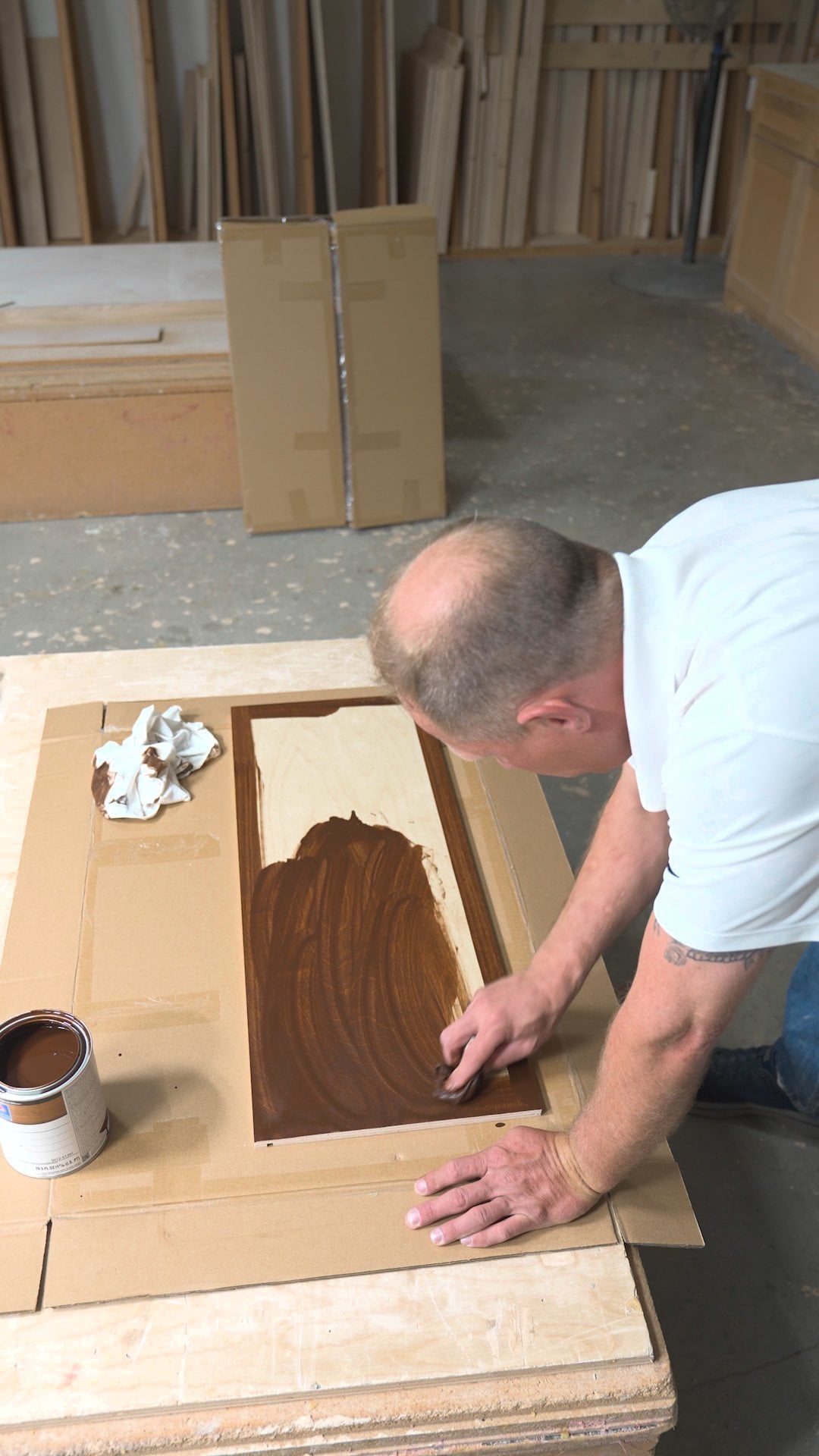 Wiping oil-based stain onto a birch shaker door with a cotton rag